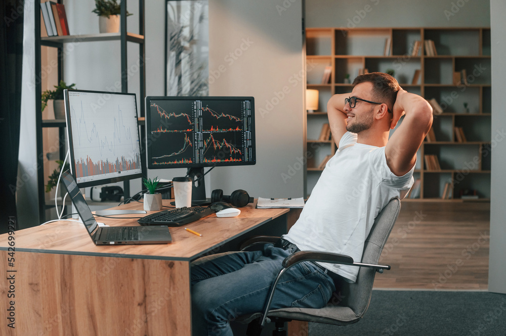 Poster laptop is on the table. young stock broker is working in the office by using computer