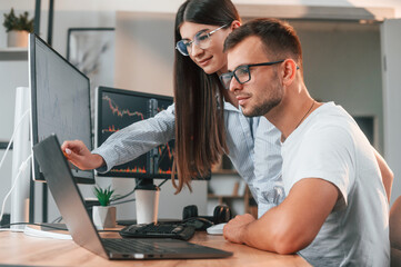 Analyzing information from computer screens. Two stock brokers is working together in the office...