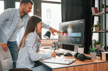 Using computer. Two young designers is working together in the office