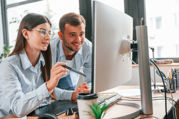 Using computer. Two young designers is working together in the office