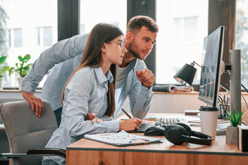 Using computer. Two young designers is working together in the office