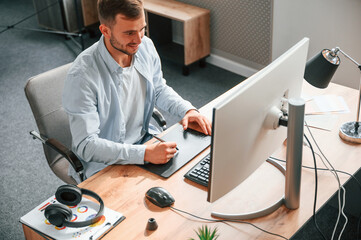 Top view. Designer is sitting by the computer and using graphics tablet with stylus © standret