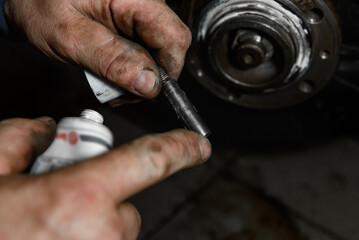 A man lubricates wheel bolts with grease.