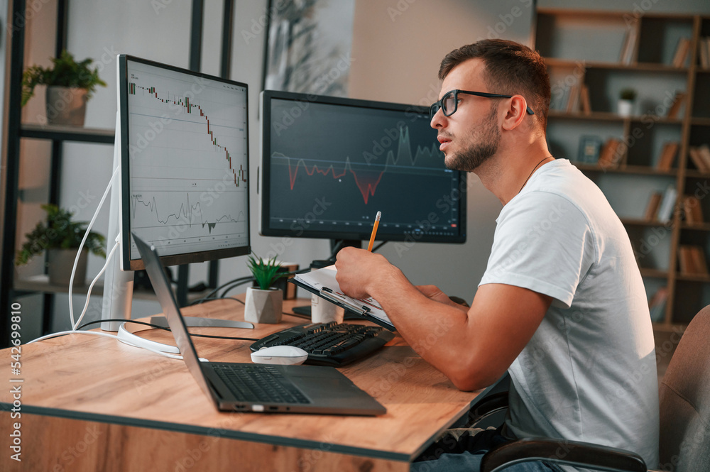 Poster laptop is on the table. young stock broker is working in the office by using computer