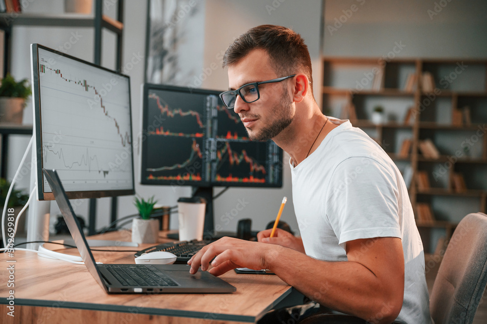 Poster young stock broker is working in the office by using computer
