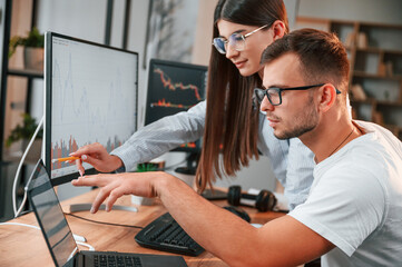 Analyzing information from computer screens. Two stock brokers is working together in the office...