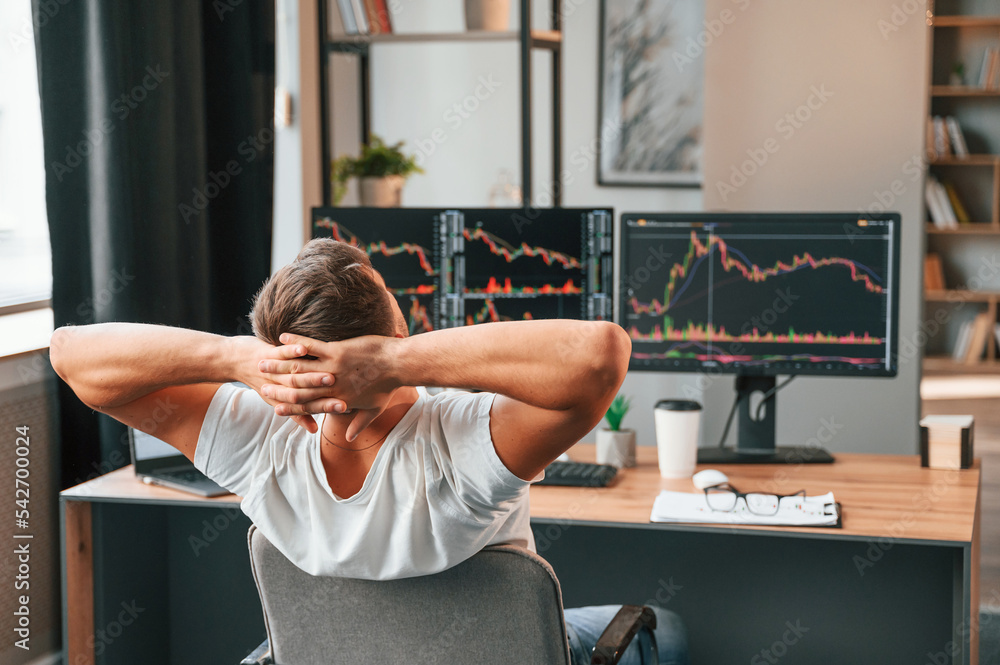 Poster taking a break. young stock broker is working in the office by using computer