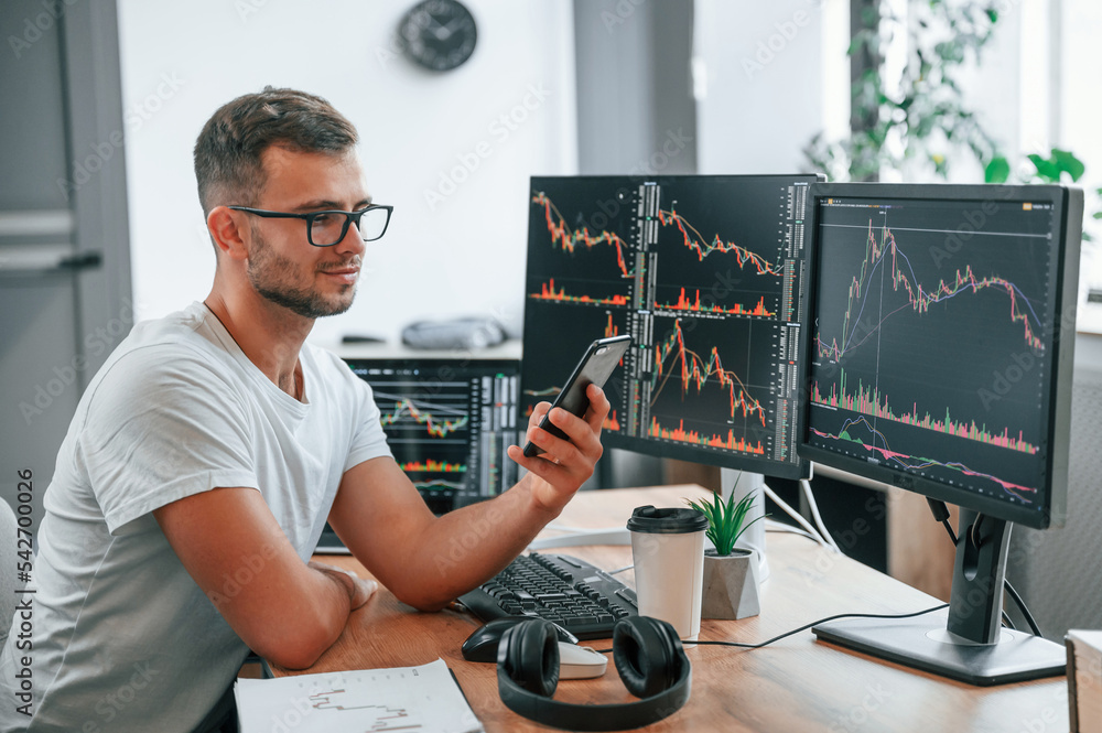 Poster young stock broker is working in the office by using computer