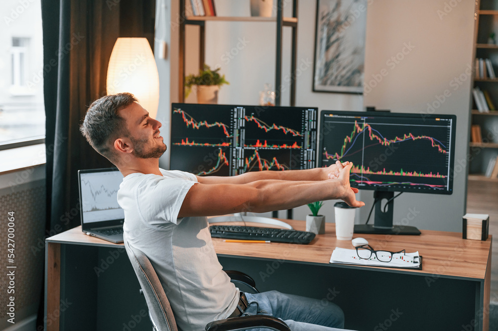 Poster taking a break. young stock broker is working in the office by using computer