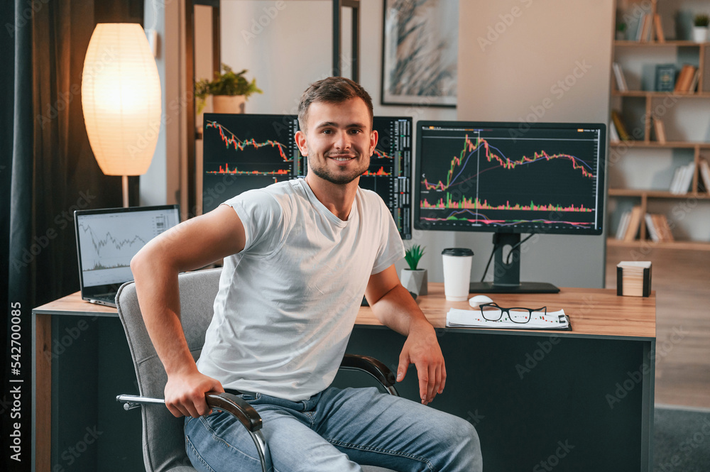 Poster young stock broker is working in the office by using computer