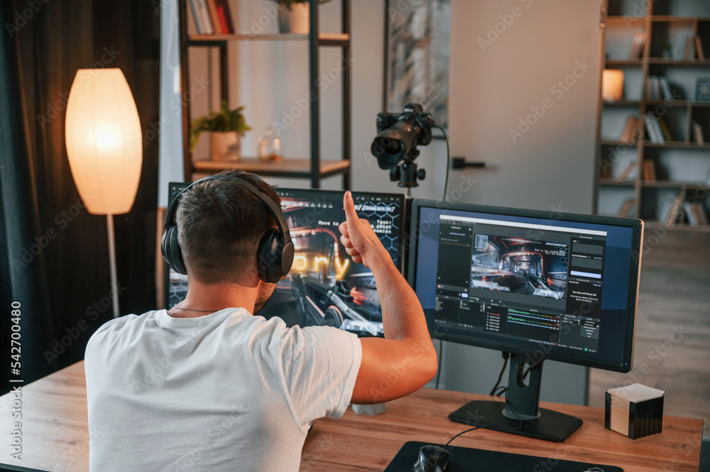 Poster recording is on. showing thumb up. young man playing and streaming the first person shooter game