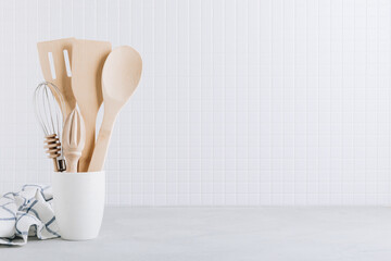 Kitchen utensils. Kitchen wooden tools and kitchenware. White modern kitchen interior background.