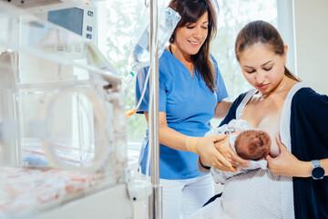 Positive friendly female breastfeeding consultant teaching new mom to breastfeed infant at hospital.