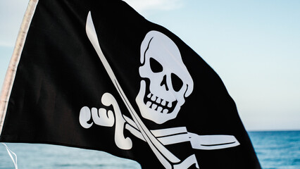 Black pirate flag with skull symbol on the desert island