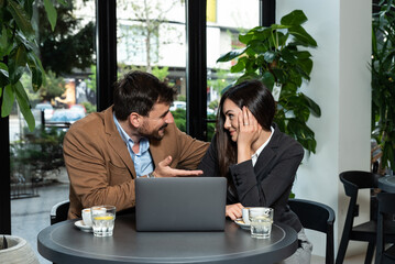 Young business man using free time of coffee or lunch break to flirt with his female colleague. Business people sitting in cafeteria flirting and small talk chatting about everything.