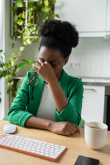 Tired African American woman freelancer wiping eyes after working long hours at computer has vision...