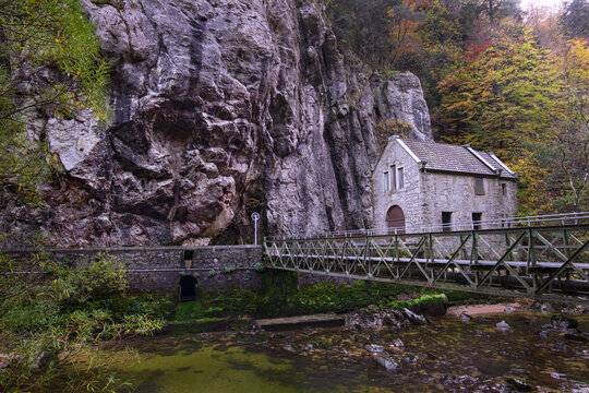 Gorges de l'Areuse, Boudry, Neuchatel, Switzerland, Europe. Beautiful romantic autumn landscape with bridge and architecture. River in the Jura Mountains. Massive rock by the riverbank.