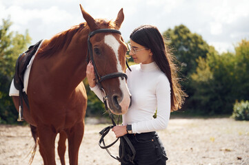 Obraz premium Side view. Young beautiful woman with a horse is outdoors