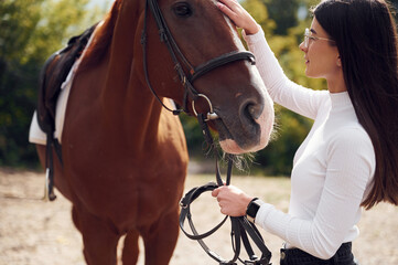Obraz premium Side view. Young beautiful woman with a horse is outdoors