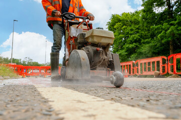 Close up and selective focus of the petrol powered road saw with dimond blade cutting asphalte road...