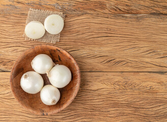 Fototapeta na wymiar White onions in a bowl over wooden table with copy space