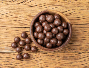 Chocolate malted balls on a bowl over wooden table