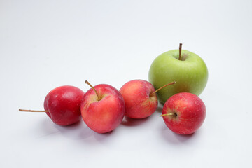 Small red Autumn Strawberry shaped Apple compare large green apple  on white background