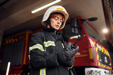 Using radio transmitter. Woman firefighter in uniform is at work in department