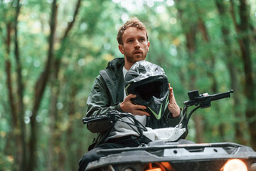 With safety helmet. TV driver is in the forest, having a ride at daytime