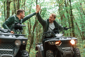Giving high fives by the hands. Two male atv riders is in the forest together © standret