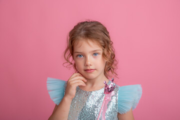 cute little girl in a beautiful dress holding a fairy magic wand on a pink background