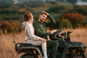 Lovely young couple is with quad bike outdoors on the field