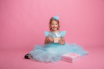 little girl sitting celebrating birthday on pink background, beautiful princess 