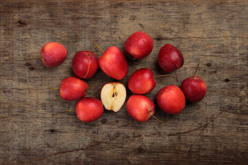 Small red Autumn Strawberry shaped Apple cut slice seed on rustic wooden background