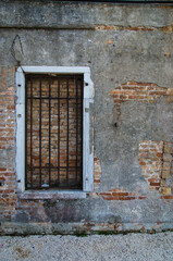 Una finestra murata e chiusa da una grata metallica all'interno dell'Arsenale di Venezia