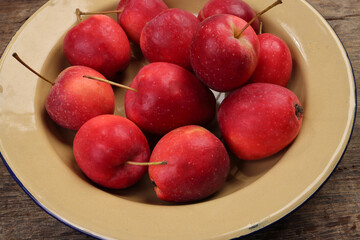 Small red Autumn Strawberry shaped Apple cut slice seed in enamel metal plate on rustic wooden background