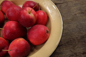 Small red Autumn Strawberry shaped Apple cut slice seed in enamel metal plate on rustic wooden background