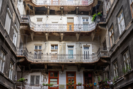 Backyard Of An Old, Large Apartment Building In The Old Town Of Budapest Hungary. Lots Of Windows, Doors And Metal Railings. Grey Walls And No People. City Trip, Tourism, Airbnb