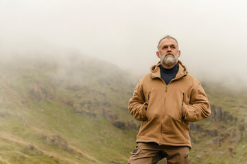 Bearded Man reaching the destination and on the top of mountain at sunset on autumn day Travel Lifestyle concept The national park Lake District in England