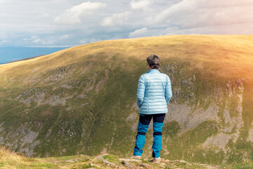 Fototapeta premium Woman reaching the destination and on the top of mountain against cloudy blue sky on autumn day Travel Lifestyle concept The national park Lake District in England