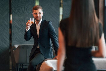 Man in suit is talking with woman that is in black dress on the party