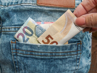 hand, die Geld in die hintere Hosentasche steckt