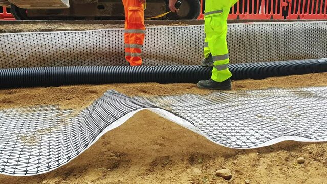 Groundworkers installing new electric ducts during roadworks on construction site	