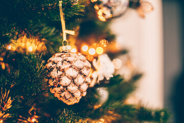 Christmas vintage toy pine cone on Christmas tree. Holiday background with bokeh lights