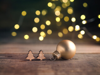 Golden Christmas tree ball with small wooden tree shapes with blurred Christmas lights