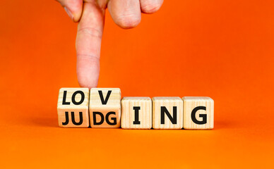 Loving or judging symbol. Concept words Loving or Judging on wooden cubes. Businessman hand....