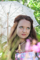 Beautiful young woman with long hair and umbrella retro style on summer meadow