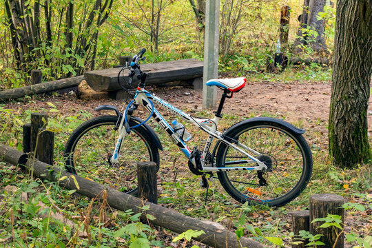 Modern bike parked in a city park, in a wooded area. Russia, Perm - September 14, 2022.