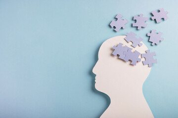 Head silhouette with puzzles inside on pastel blue background. Mental health concept, Alzheimer...