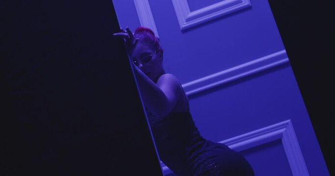 Beautiful sexy woman in short dress or swimwear dancing middle of doorway . Sensual scene of female model doing different sexy movements . Erotic performance in privat room of strip poledance club